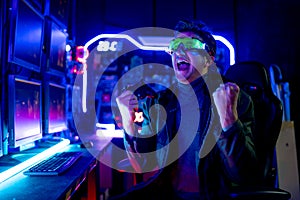 Caucasian Gamer man with hitech clothes and eye glasses show action of excited and happy during play computer game in room with