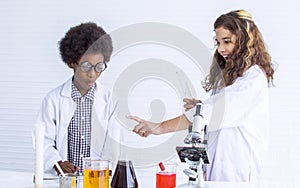 Caucasian girl and African black boy studying Science and doing experiment together in classroom at school. Education and