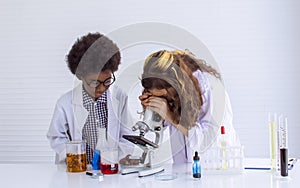 Caucasian girl and African black boy studying Science and doing experiment together in classroom at school. Education and