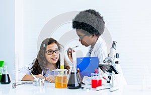Caucasian girl and African black boy studying Science and doing experiment together in classroom at school. Education and