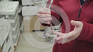 Caucasian girl buys large, transparent glass for martinis and cocktails in store