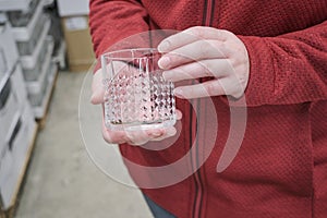 Caucasian girl buys a transparent glass for strong alcoholic beverages in store