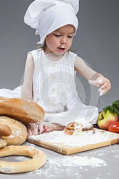 Caucasian Girl in Cook Hat and Lips in Flour Sitting in Front of Fresh Buns