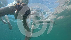 Caucasian girl dives under sea water in background of other. Underwater view