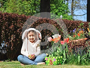 Caucasian girl with easter candy eggs in the palms on the lawn.