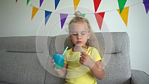 Caucasian girl eats white bread and drink juice. Child smiling looking at camera