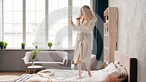 Caucasian girl happy carefree woman in bathrobe shopping online with phone and credit bank card success mobile payment