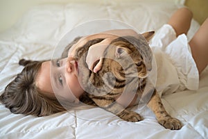 Caucasian girl hugging cat on bed