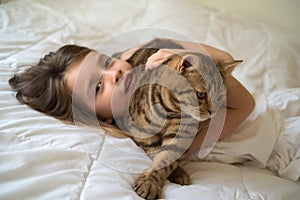 Caucasian girl hugging cat on bed