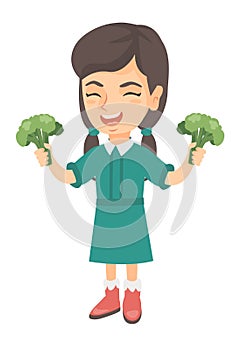 Caucasian girl laughing and holding broccoli.