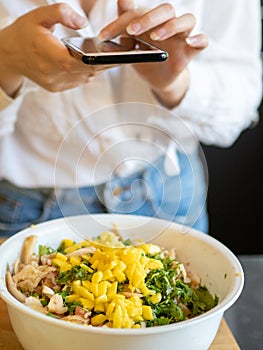 Caucasian girl in a modern kitchen, consult her cell phone to know the recipe she is going to prepare with vegetables