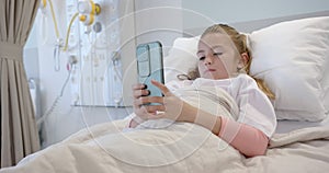 Caucasian girl patient lying in hospital bed using smartphone, copy space, slow motion