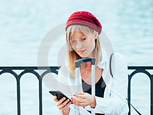 Caucasian girl in a red beret, talking on the phone by the lake fence of the Parque del Retiro in Madrid, Spain