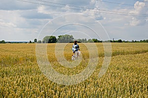 Caucasian girl riding bicycle on wheat field, countryside ukraine. vintage photo. Girl on a bike in the countryside. Portrait of a