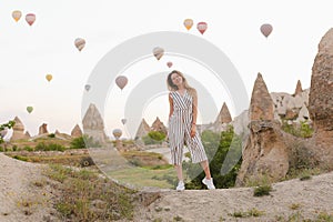 Caucasian girl standing with hot air balloons and rocks on background in Capadocia.