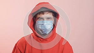 Caucasian girl in studio on white background nervously looks around, in medical protetive mask inscription 2019-nCov. Coronavirus