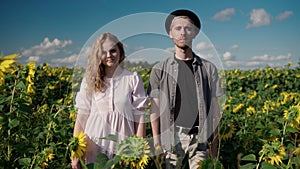 caucasian girl in sunflower field posing on the phone camera with a guy in hat