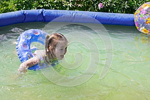 Caucasian girl swimming in the pool outdoors, child 4 years old playing in the backyard, horizontal photography