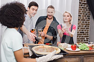 caucasian girl taking photo of african american friends pizza