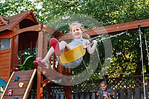 Caucasian girl toddler on swing on backyard playground outside