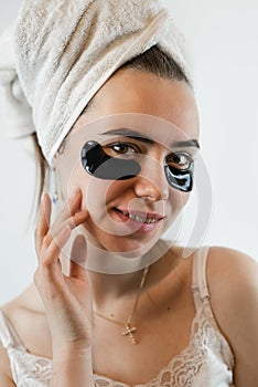 caucasian girl in towel with black patches under eyes isoalted on white