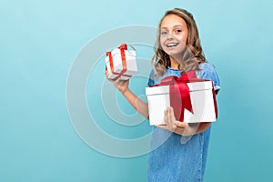 Caucasian girl with wavy brown hair in blue dress, big hat holds a boxes with gifts and rejoices
