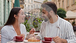 Caucasian girlfriend feeding boyfriend a croissant man woman couple together happy family enjoy fun smile laugh city