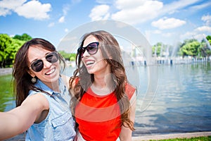 Caucasian girls making selfie background big fountain. Young tourist friends traveling on holidays outdoors smiling