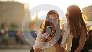 Caucasian girls making selfie background soft sunset light. Young tourist friends enjoy weekend outdoors smiling happy.