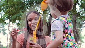 Caucasian girls, siblings playing with soap bubbles on fresh air. Older girl amuse, entertain little girl in the age of