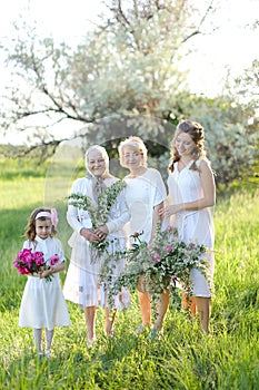 Caucasian granny in white dress with daughter and granddaughters outside.