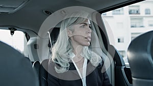 Caucasian gray-haired women sitting in backseat of moving car.