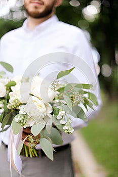 Caucasian groom waiting for bride with bouquet, focus on flowers.