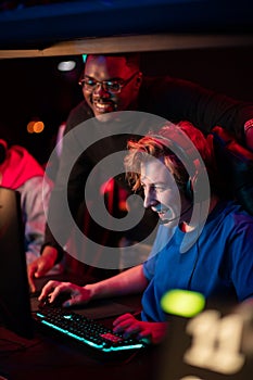 Caucasian guy shows his black friend how to play a video game in a computer club