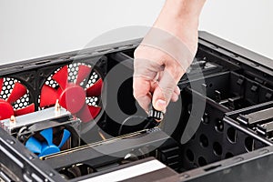 caucasian hand connecting or disconnecting power connector of GPU card in opened black miditower PC case