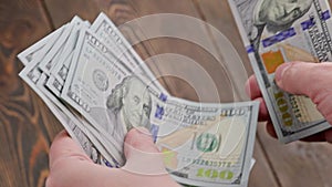 caucasian hand counting small stack of hundred us dollar banknotes