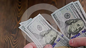 caucasian hand counting small stack of hundred us dollar banknotes