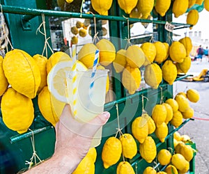 Caucasian hand with healthy fresh lemonade during summer - lemons background