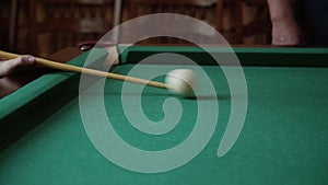 Caucasian hands of man with a cue hit the ball on a pool table