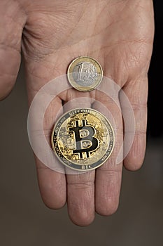 Caucasian hands shows one Bitcoin coin and one Euro Coin. New finance concept. Comparison between currencies, fiat and crypto