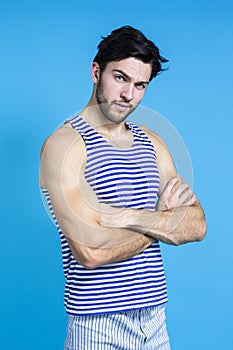 Caucasian Handsome Brunet Man in Striped Underware During Early Morning Posing With Hands Folded In Front Against Seamless Blue