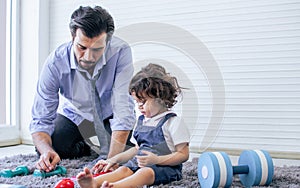 Caucasian handsome father taking care, playing toys with his little cute daughter on floor in cozy living room at home after work