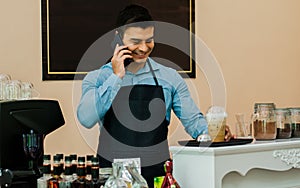 Caucasian handsome male bakery cafe business owner or entrepreneur smiling with happiness, success, holding and talking mobile