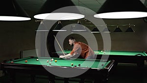 Caucasian handsome man near billiard table with green surface and balls in the billiard club.Pool Game concept.