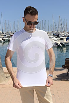 Caucasian handsome young man showing white t-shirt. Lifestyle summer mockup.