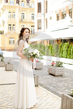 Caucasian happy bride walking with bouquet of flowers in city.