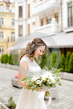 Caucasian happy bride walking with bouquet of flowers in city.