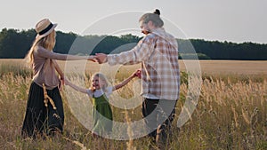 Caucasian happy family farmers woman in hat bearded man and child girl parents and little daughter kid holding hands