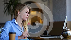 Caucasian happy female waving hand chatting online on video call on laptop in restaurant. Close up. Young woman with cup