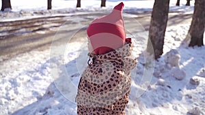 Caucasian happy preschool girl plays with snow on a sunny winter day in a park